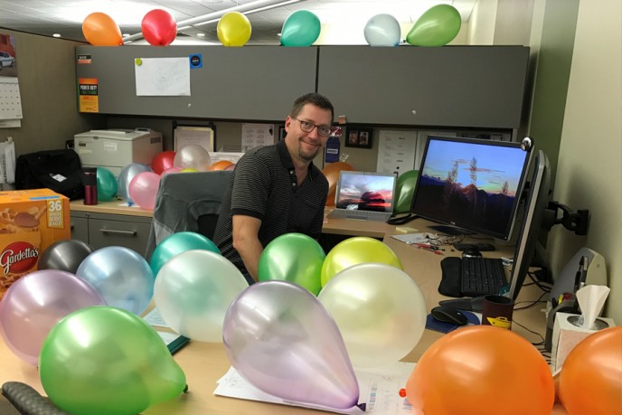 Team member at desk surrounded by balloons