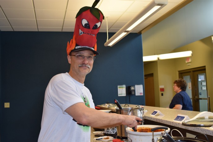 Employee wearing chili pepper hat cooking chili
