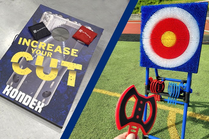 a bag-tossing game next to an ax-throwing game. A hand is holding one of the axes