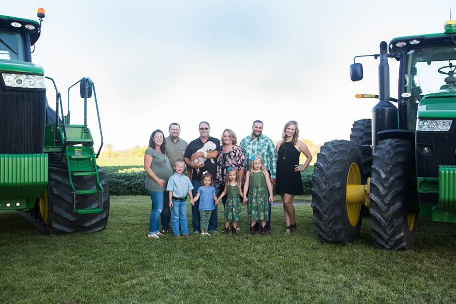 Stetzel family photo near their farm field and John Deere equipment