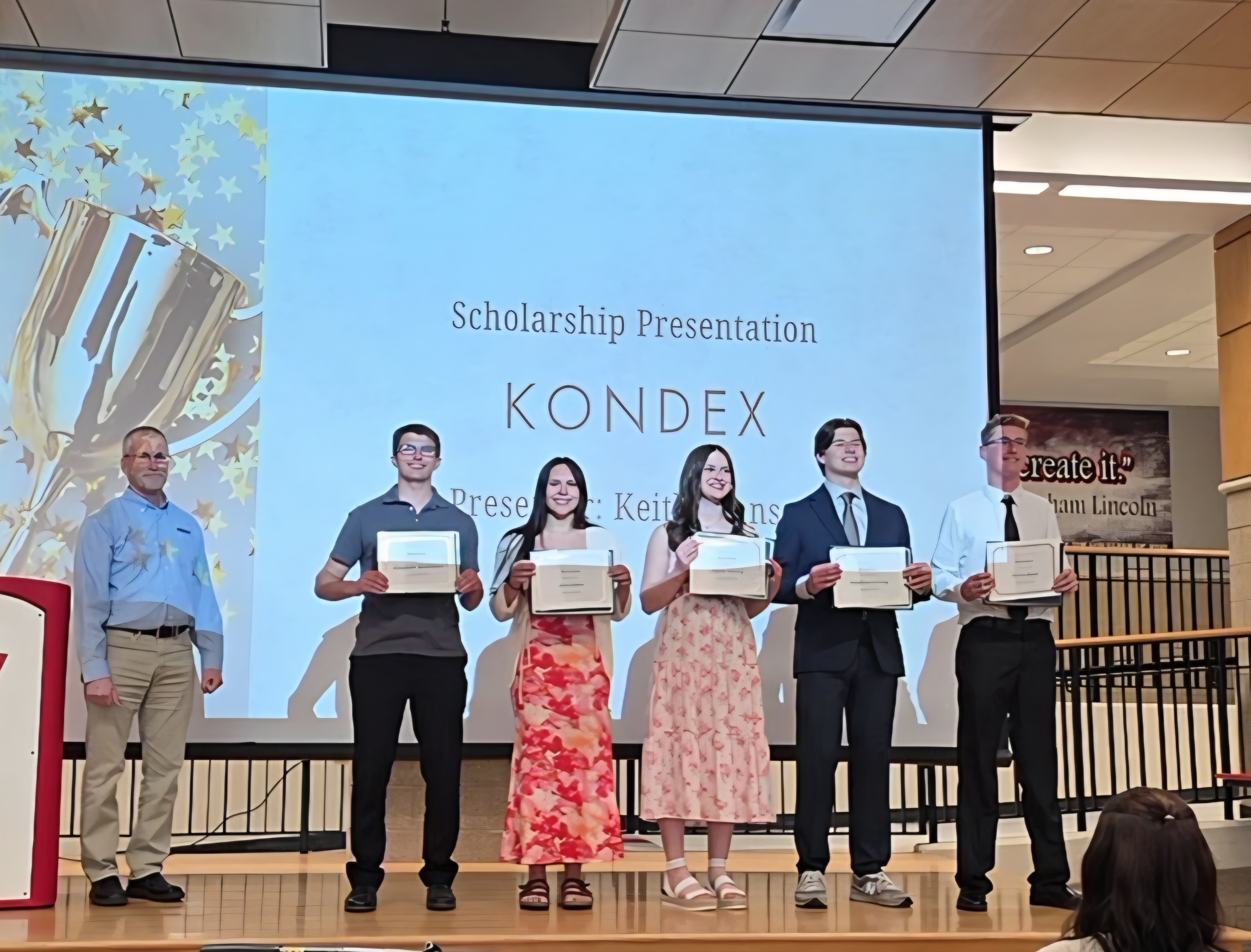 Keith Johnson and scholarship recipients standing shoulder to shoulder on stage