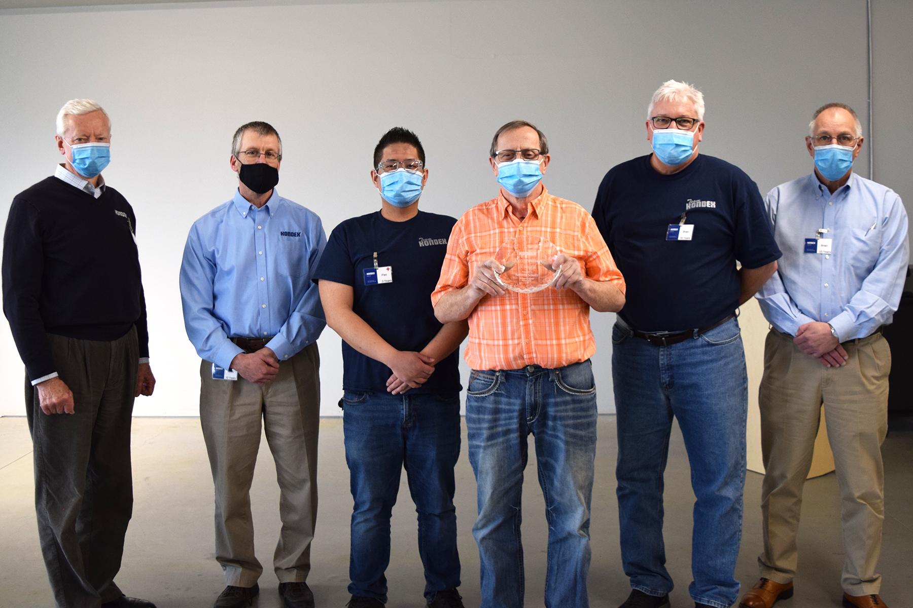 Ken holding a retirement plaque surrounded by members of Kondex management